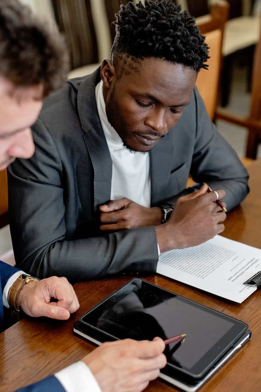 a man in gray suit looking at the tablet on a wooden table